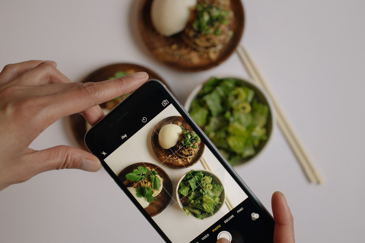料理をスマートフォンで撮影している手元